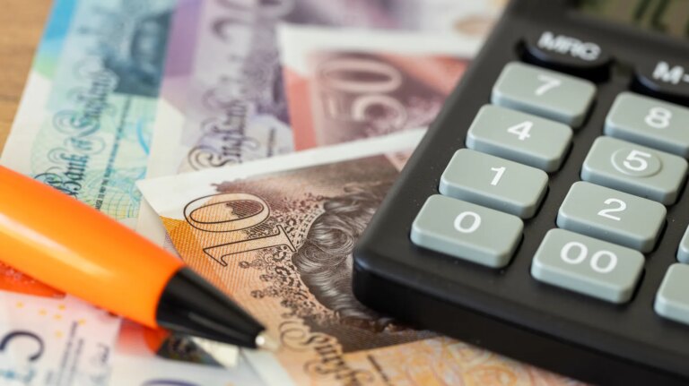 British bank notes next to a calculator and pen