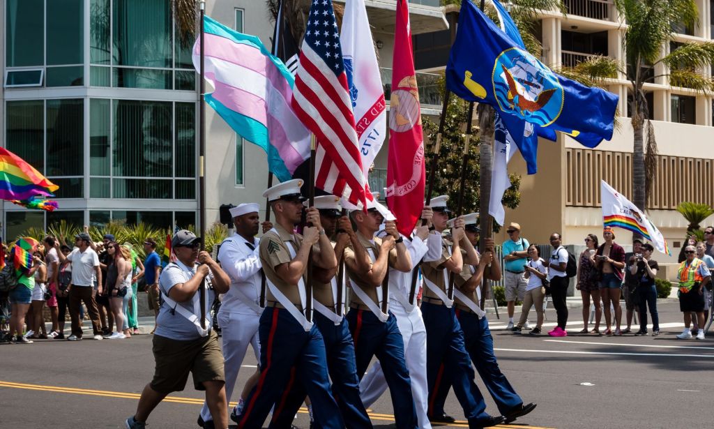Les membres du service militaire américain détenant une variété de drapeaux, y compris le drapeau américain et le drapeau trans.