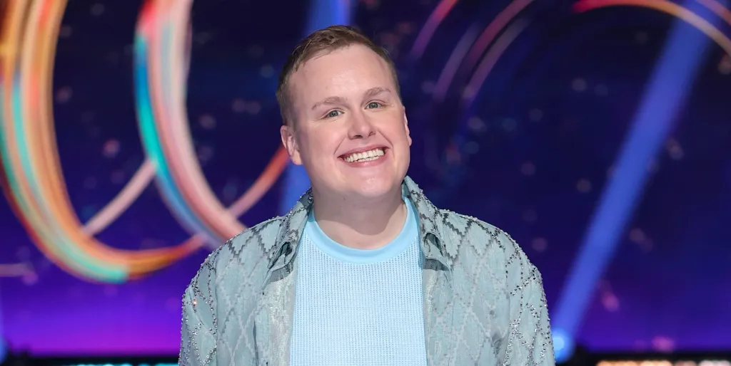 Josh Jones dans un t-shirt bleu et une surchemise bleue, souriant lors d'un appel photo pour Dancing On Ice