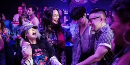 A still from The Wedding Banquet featuring Kelly Marie Tran, Lily Gladstone, Han Gi-chan, and Bowen Yang dancing in a club.