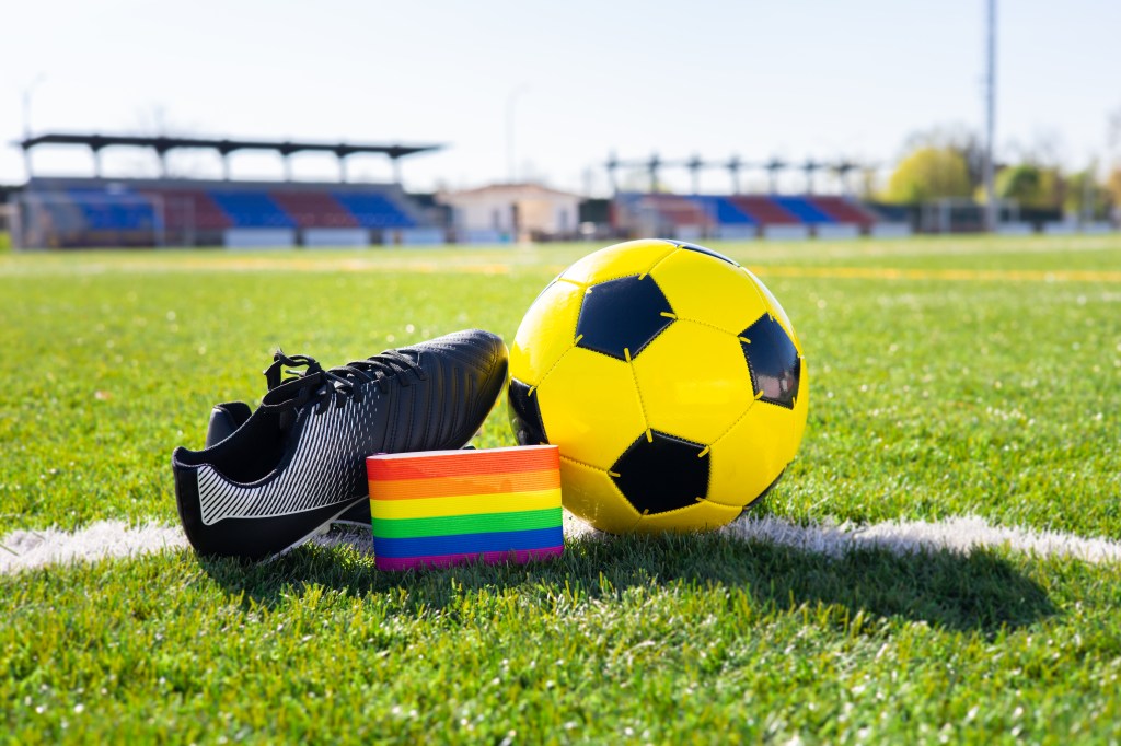 Couleurs arc-en-ciel de la fierté LGBTQ + sur un brassard à côté d'une botte de football et de football.