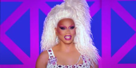 A still of RuPaul smiling during a performance on Drag Race UK season 3