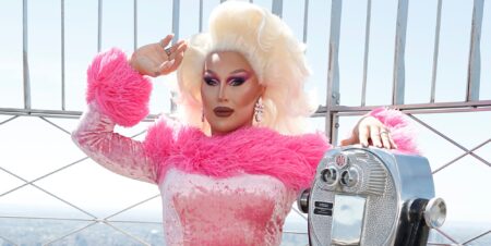 The Vivienne at the top of the empire state building in a pink outfit.