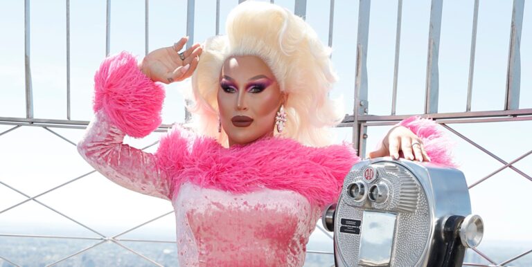 The Vivienne at the top of the empire state building in a pink outfit.