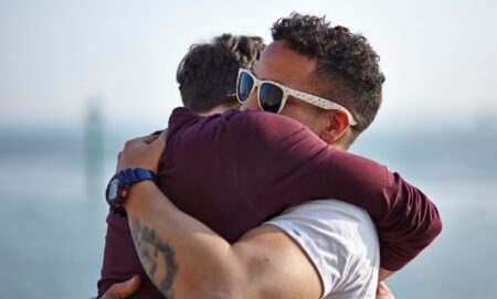 Two middle-aged men hug each other.