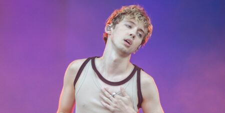 Troye Sivan holds his chest as he performances at Primavera Sounds 2024 in a vest top.