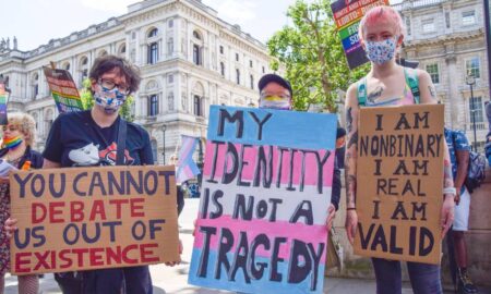 several people hold up signs during a trans rights protest one reads