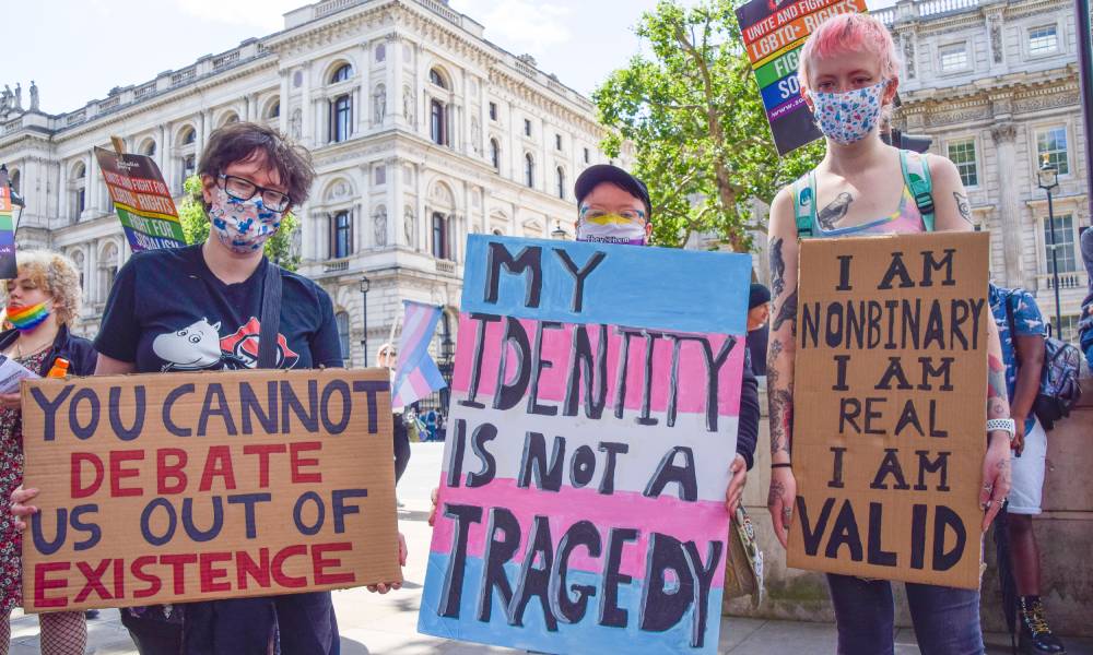 several people hold up signs during a trans rights protest one reads