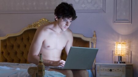 A shirtless man using a laptop computer