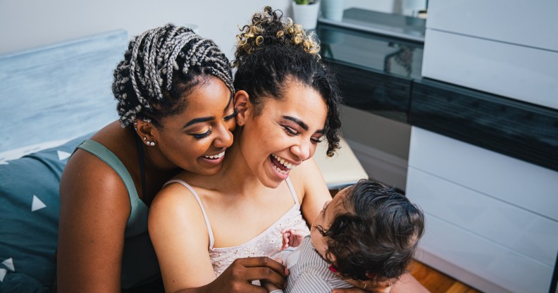 Vue à angle élevé des mères lesbiennes gaies jouant avec un fils adopté dans le salon à la maison.