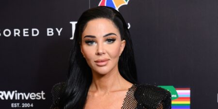 Tulisa poses at a red carpet event while standing against a black and white background.