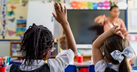 Les élèves du primaire assis dans une salle de classe sont enseignés par un enseignant.
