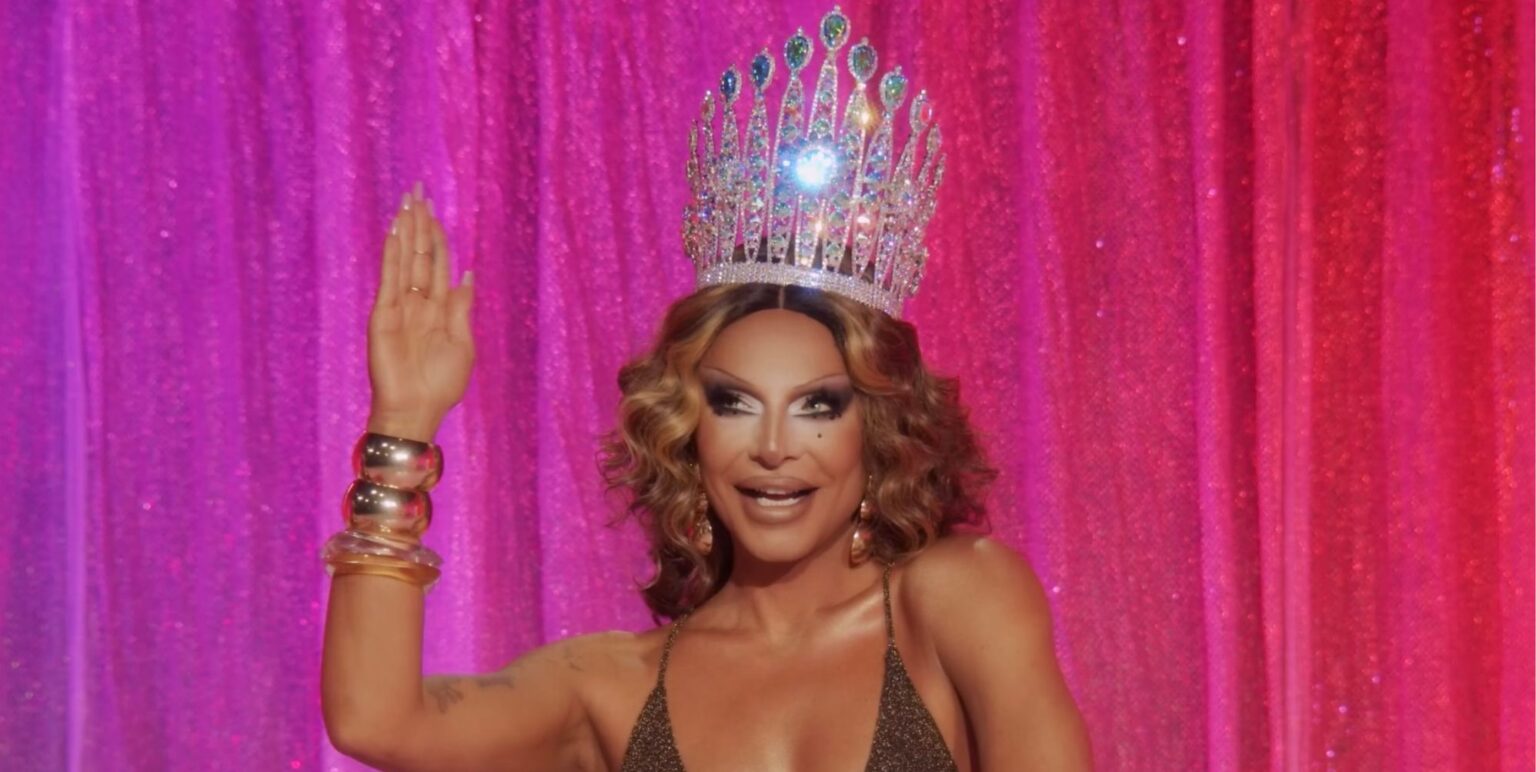 Raven appears in episode 10 of Drag Race All Stars 10. She is wearing a large crown and waving.