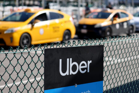An image of two yellow taxi cabs with the uber logo in the foreground