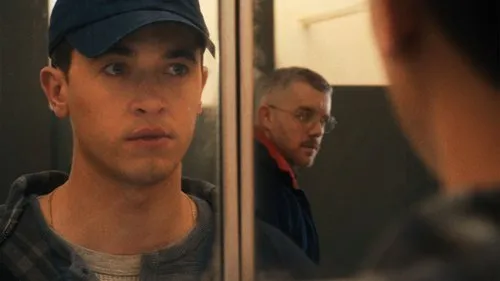 Tom Blyth and Russell Tovey appear in Plainclothes. Blyth is looking at Tovey through a bathroom mirror.