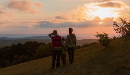 LGBTQ+ couple and child going for a walk during sunset.