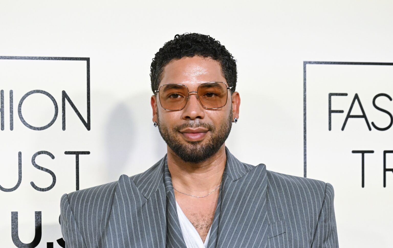 Jussie Smollett in a grey pinstruoe suit. He