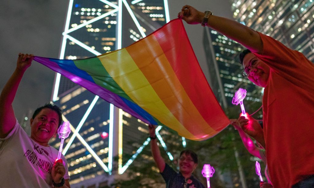 Quatre manifestants tenant un drapeau LGBTQ + Pride à Hong Kong.