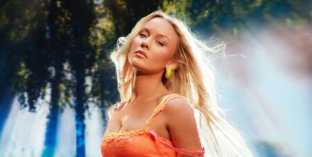Zara Larsson poses in a neon orange top for her Midnight Sun album.