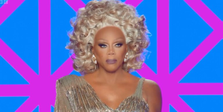 RuPaul in a gold shiny dress on the judging panel of Drag Race UK season 7.