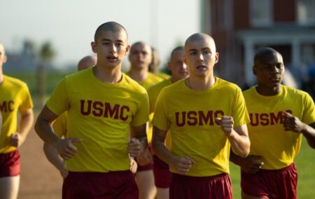 Boots still, several boys with shaved heads, all wearing yellow shirts and red shorts, running.