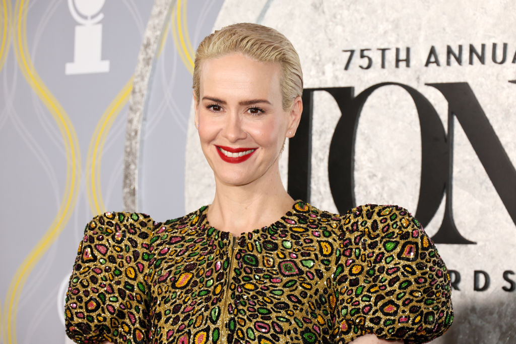 Sarah Paulson aux cheveux blonds coupés court portant une robe dorée avec des détails de paillettes métalliques
