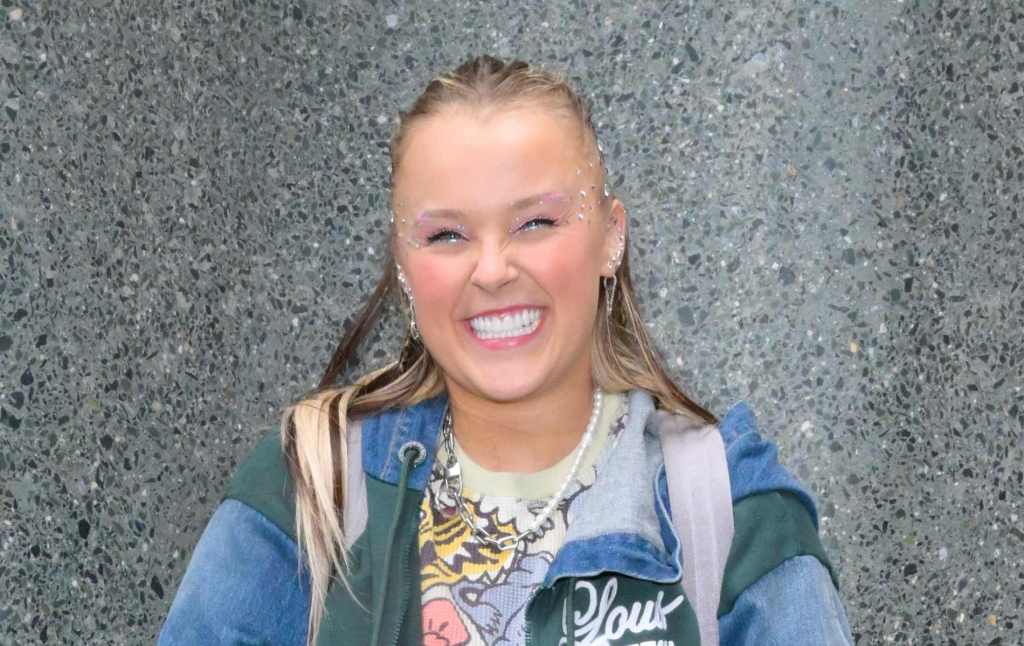 JoJo Siwa dans une veste multicolore souriante.