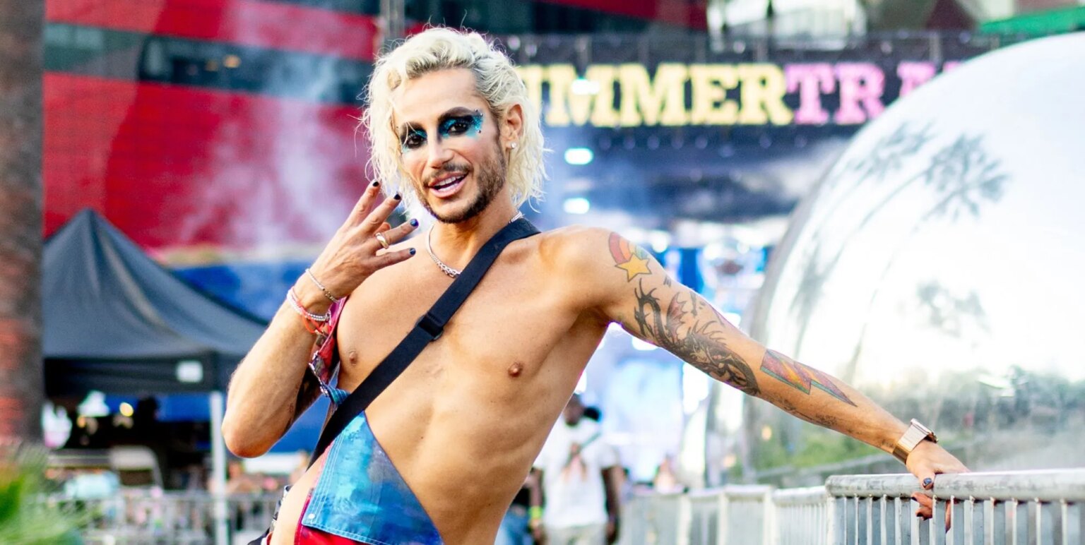 Frankie Grande parle en faveur des power bottoms : « Vous en avez besoin » Frankie Grande poses shirtless, wearing shiny blue bottoms and a black strap and heavy makeup, holding his hand to his face.