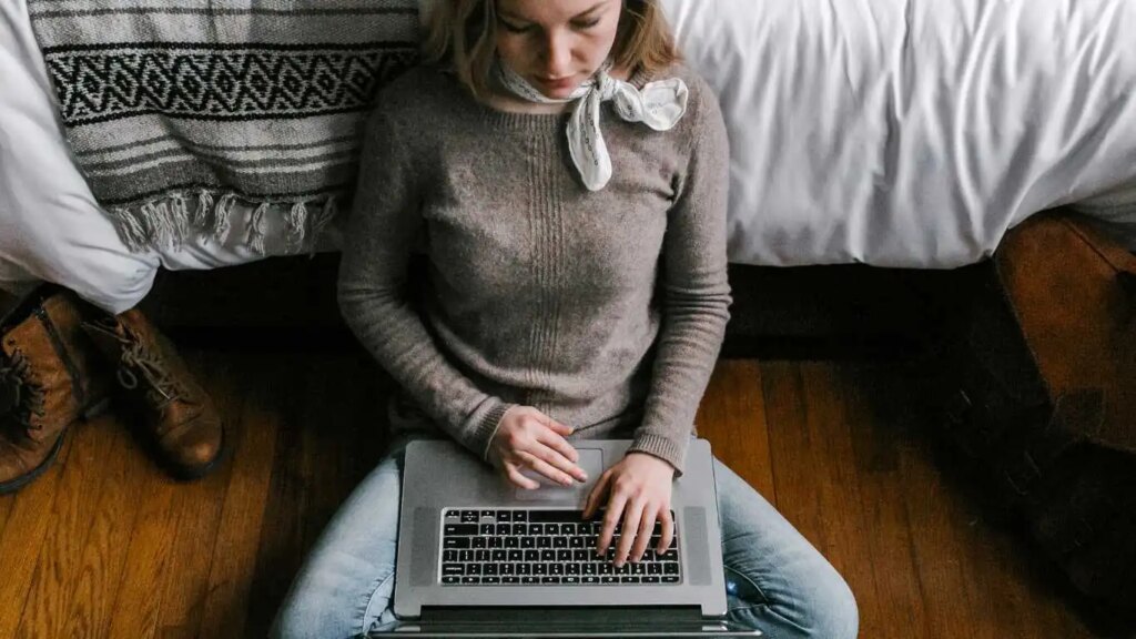 La ligne d'assistance téléphonique d'Hawaï pour les jeunes queer reste ouverte pendant les vacances Girl sits on the floor with a laptop over her legs.