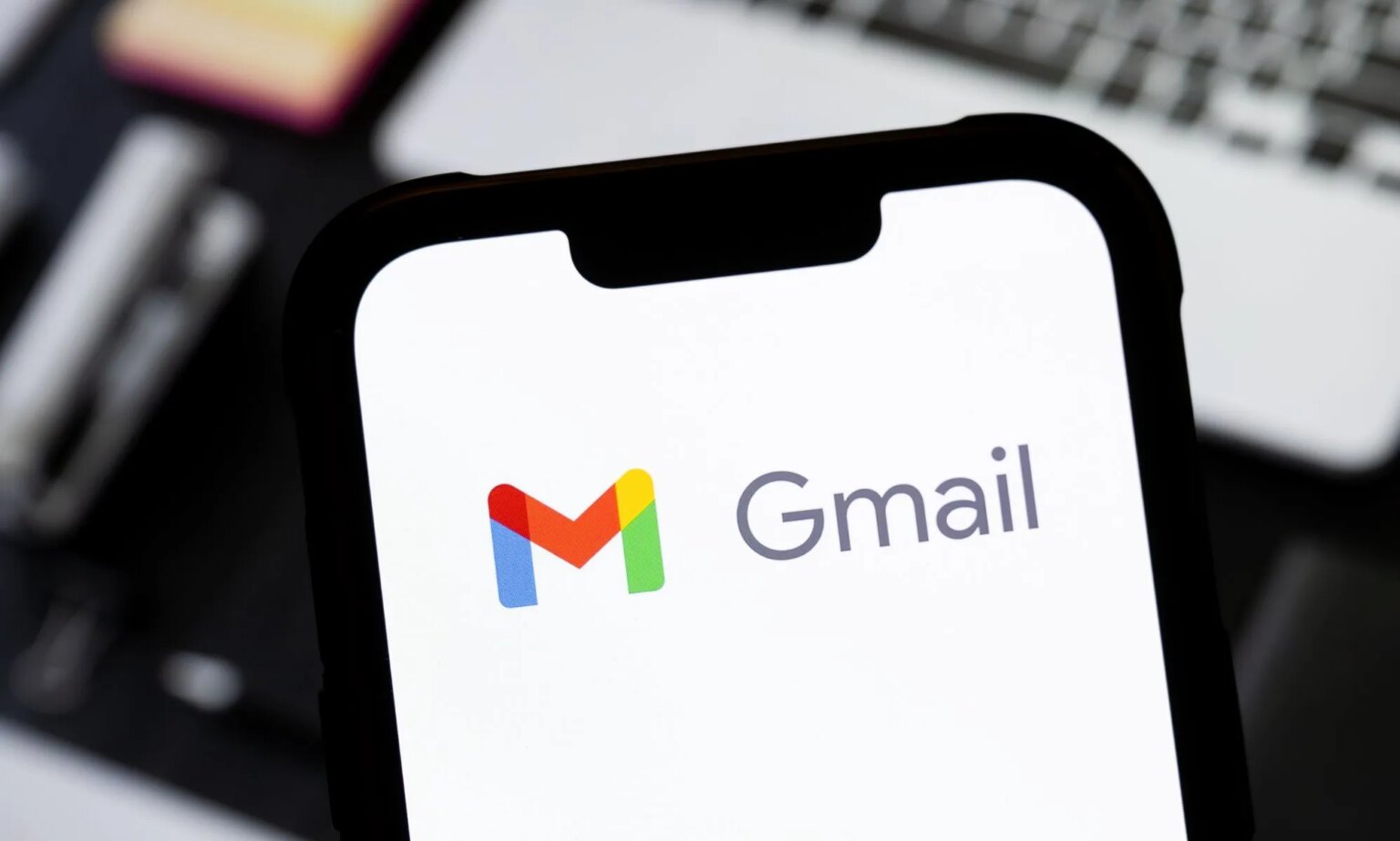 Les personnes trans pourraient supprimer le « nom mort » de l'adresse Gmail grâce à de nouveaux changements Someone holding a phone in front of a laptop with the Gmail logo visible.