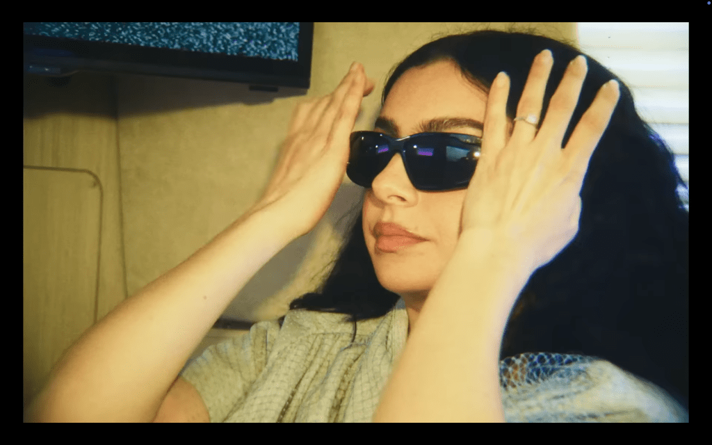 Charli XCX met des lunettes de soleil noires dans The Moment