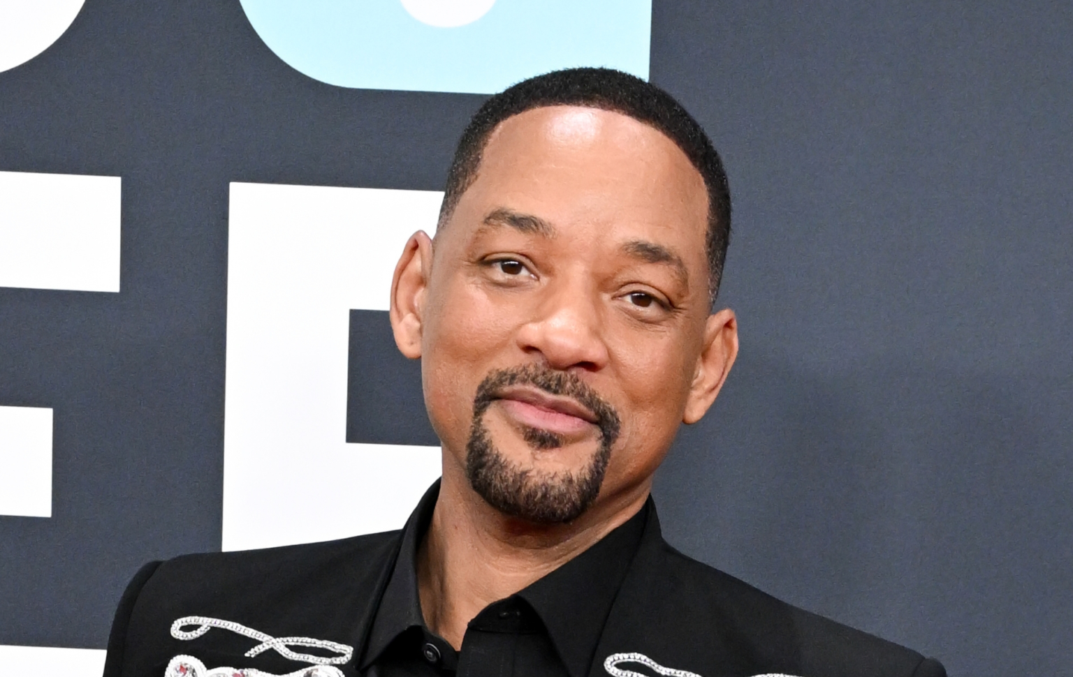 Will Smith poursuivi en justice par un violoniste de tournée pour harcèlement sexuel, licenciement abusif et représailles Will Smith at the 67th GRAMMY Awards. Wearing a black suit against a grey backgrop