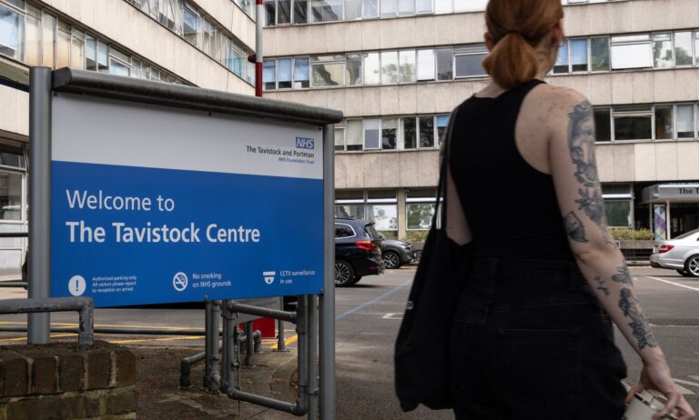 Le NHS a fermé Tavistock en raison de problèmes de soins trans – il n’y a eu que huit plaintes A person in a tank top stands outside infront of the Tavistock Centre sign.