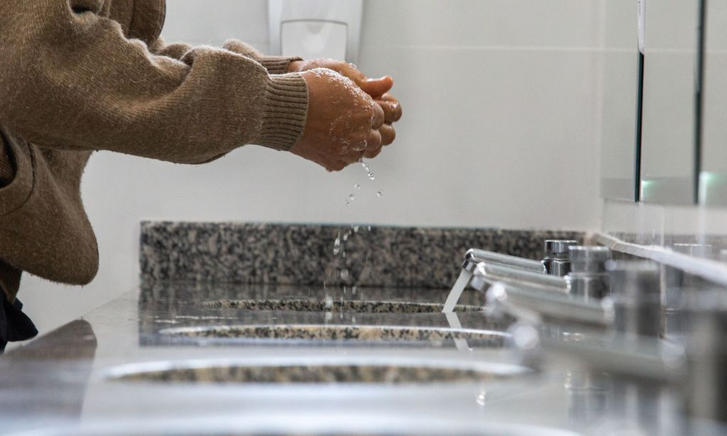 Une personne dans des toilettes publiques se lavant les mains.