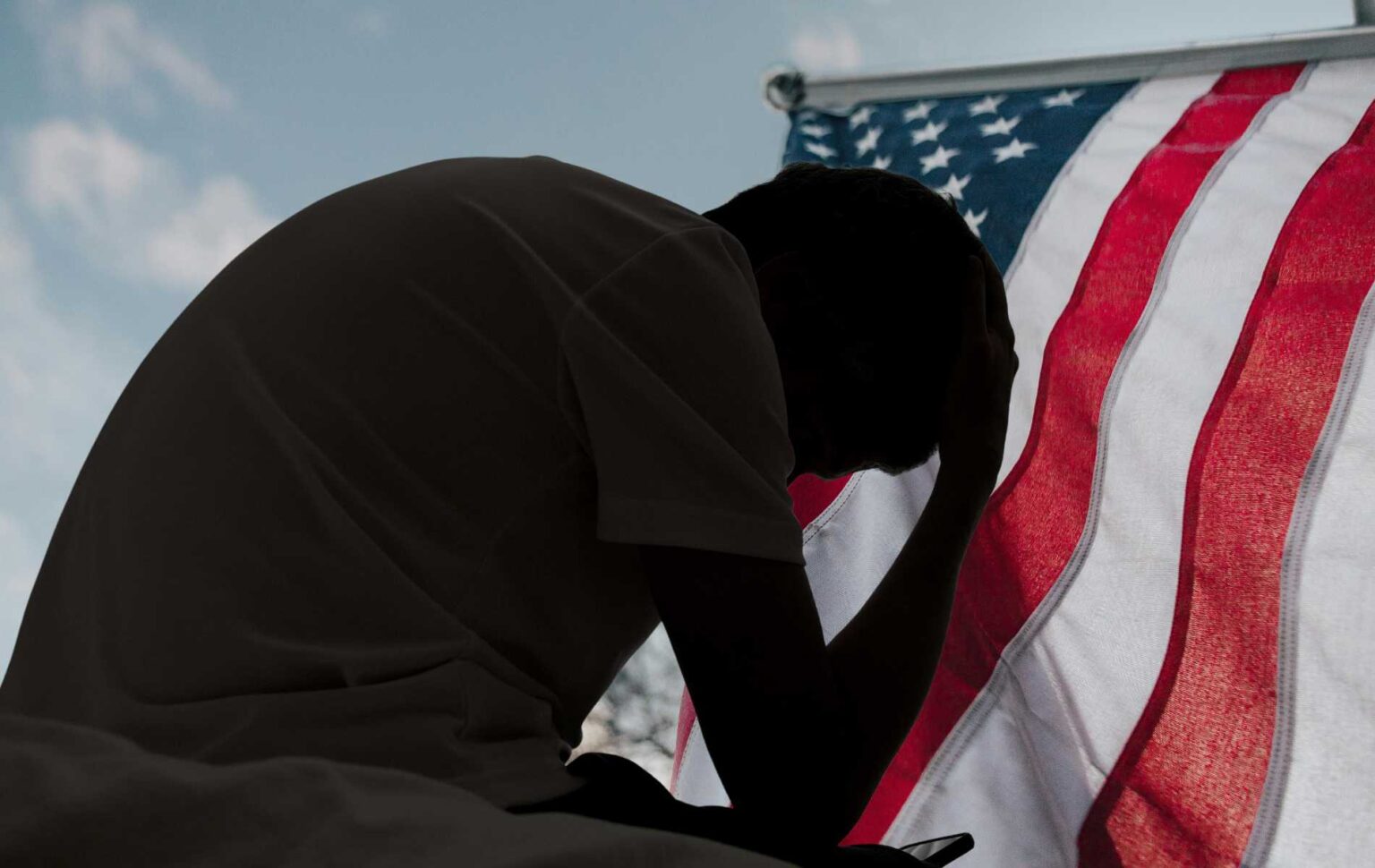 Un fan gay de MAGA est contrarié par le fait que les hommes ne veulent pas coucher avec lui et que les réseaux sociaux ne peuvent pas y faire face A distressed man in silhouette sits in dark room texting on smartphone. Blinds drawn in window light making silhouette of man with hand of forehead communicating on cell phone. Moody dark image with copy space.