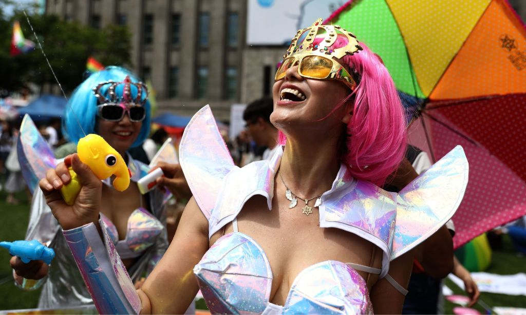 Une personne en tenue Pride utilisant un pistolet à eau.