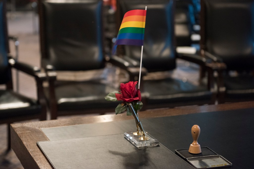Un drapeau arc-en-ciel se dresse sur une table d'audience