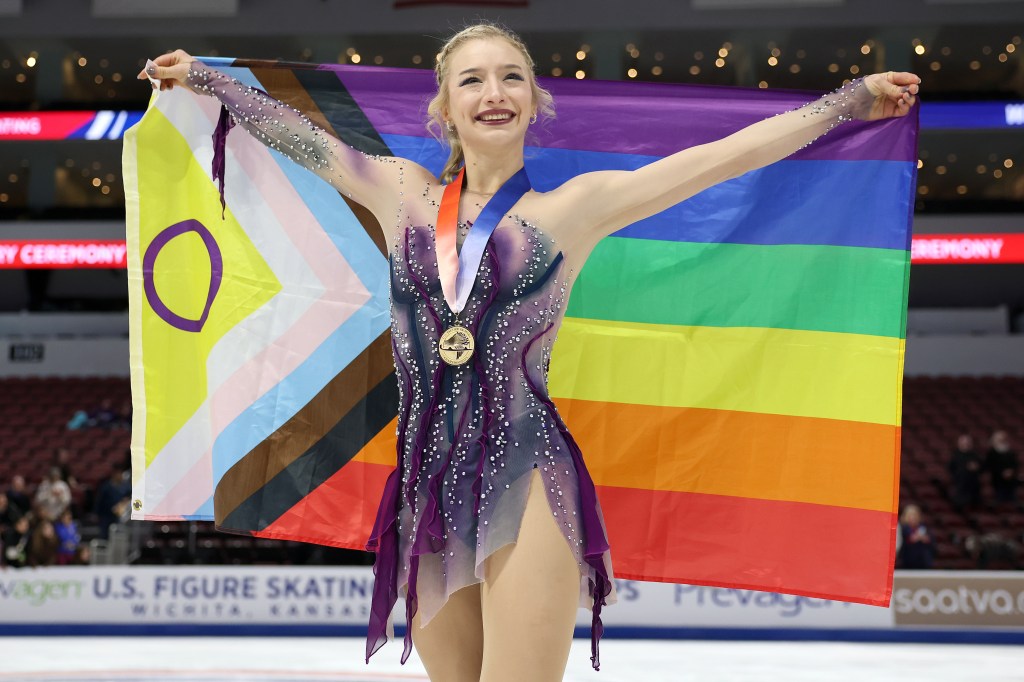 Amber Glenn pose avec la médaille d'or et le drapeau de la fierté du progrès