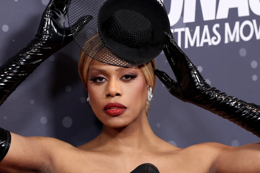 Laverne Cox portant une robe noire, des gants en cuir noirs et un chapeau noir en dentelle
