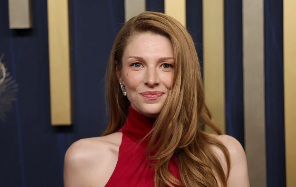 Hunter Schafer avec ses cheveux blonds détachés dans une robe rouge à col montant