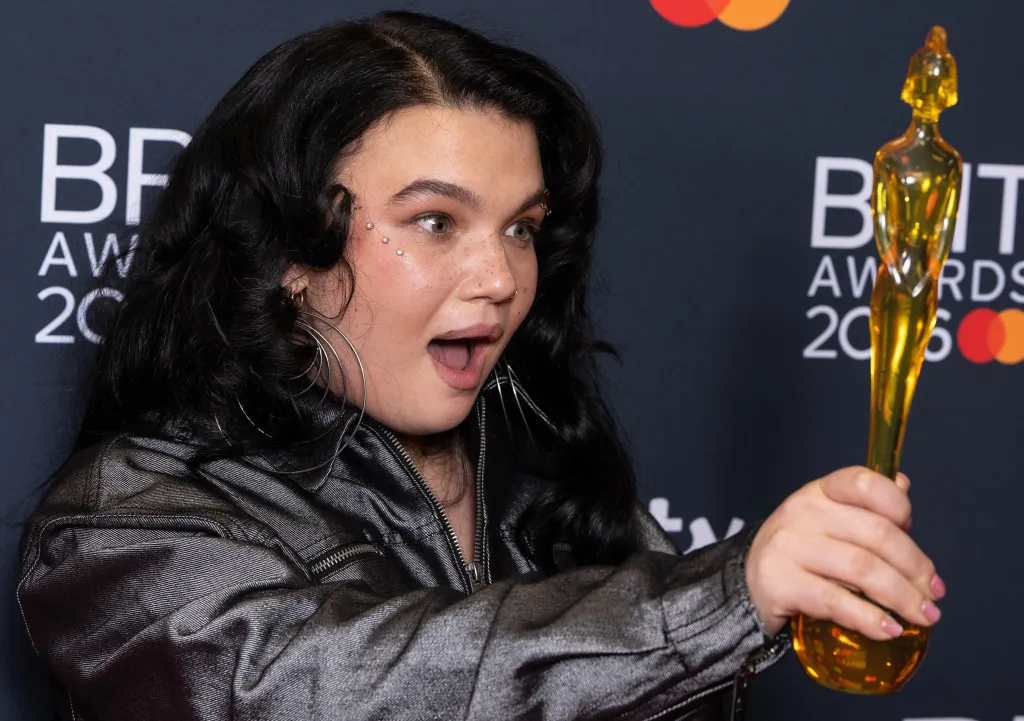 Lola Young pose avec le Breakthrough Artist Award dans une veste sombre
