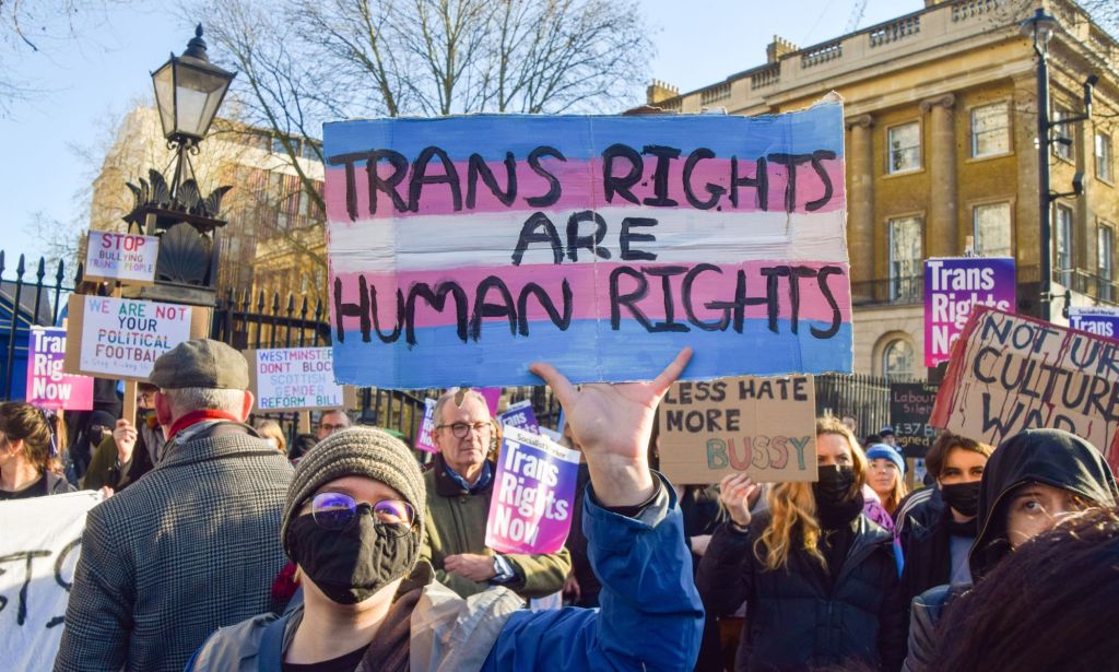 Un activiste trans brandit une pancarte "les droits des trans sont des droits humains."