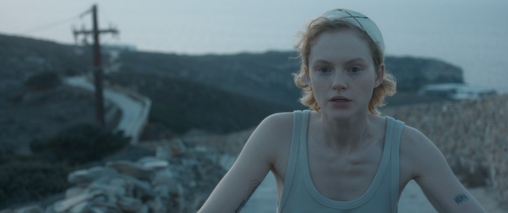 Cadre de satisfaction d'Emma Laird parcourant un chemin de terre dans un gilet gris