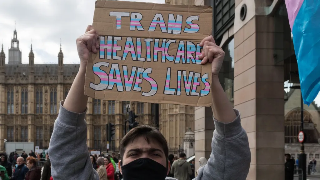 Un manifestant à Londres brandit une pancarte "les soins de santé trans sauvent des vies"