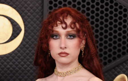 Chappell Roan attends the 68th GRAMMY Awards, wearing a gold choker and a red hood over her hair