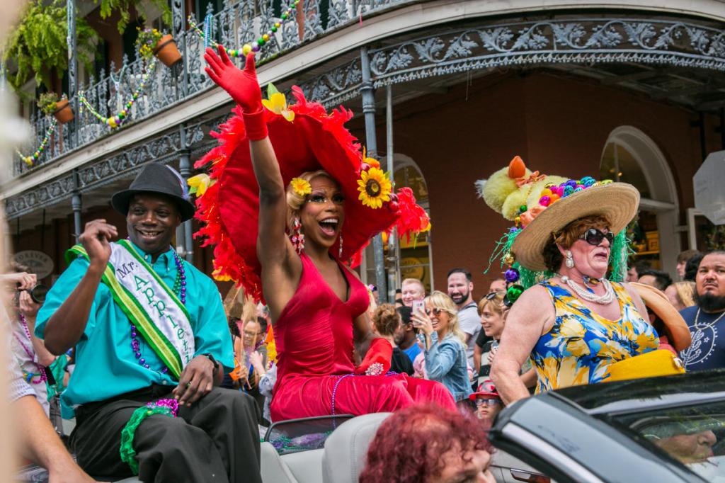 Image du Gay Easter Parade de la Nouvelle-Orléans : trois individus vêtus de tenues aux couleurs vives dans une voiture à toit ouvrant