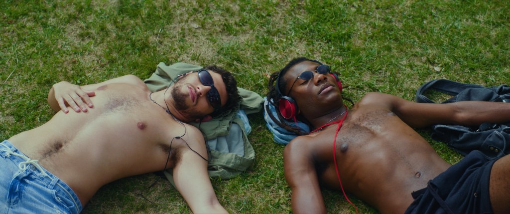 Scène de nuit : deux hommes allongés dans un parc avec des lunettes de soleil et des écouteurs