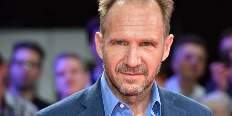 La star de Harry Potter, Ralph Fiennes, vient de soutenir cette icône queer pour incarner Voldemort Headshot of Ralph Fiennes wearing a blue shirt and blazer