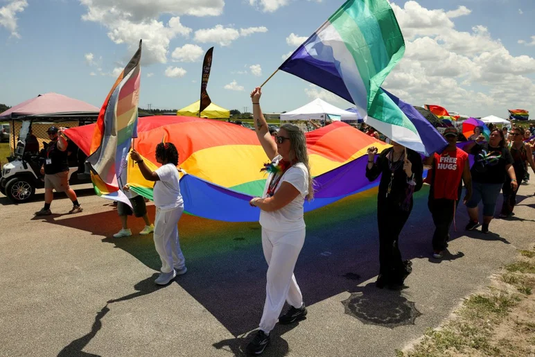 Les gens portent un grand drapeau arc-en-ciel lors du défilé lors du cinquième festival annuel de la Treasure Coast Pride Fest, le 25 avril 2026, au parc des expositions du comté de St. Lucie. L'événement était organisé par Sanctuary of the Treasure Coast.