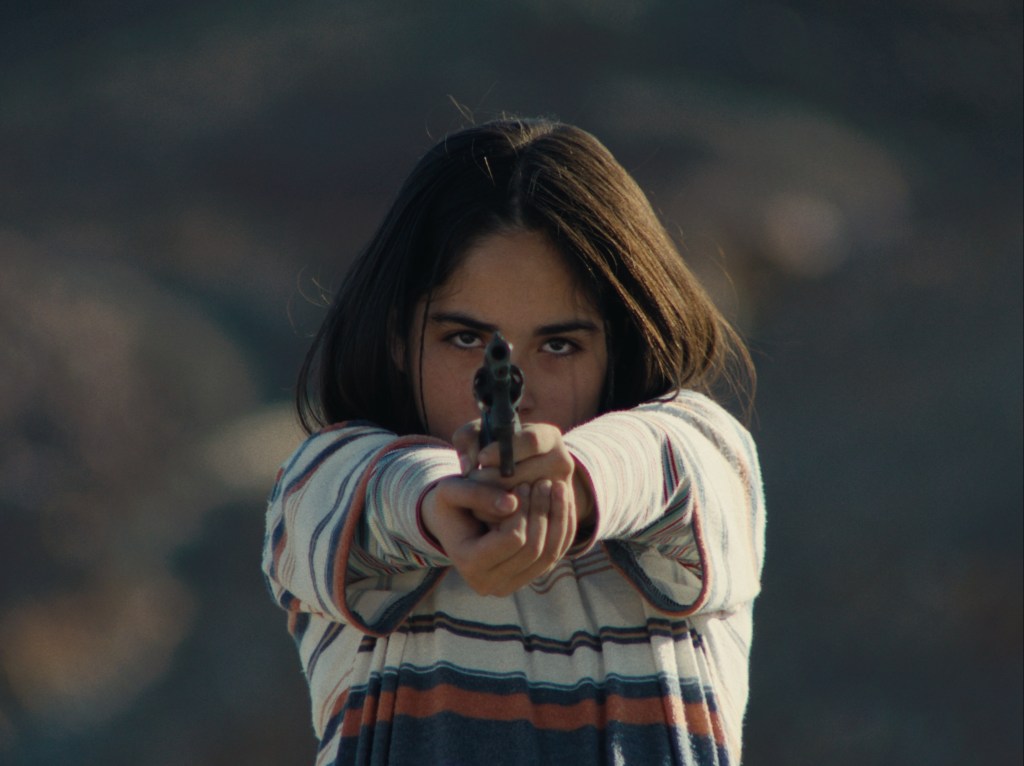 Le regard mystérieux du flamant : une jeune fille pointant une arme sur la caméra.